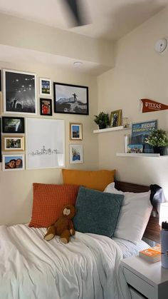 a bedroom with pictures on the wall and a teddy bear sitting on the bed in front of it