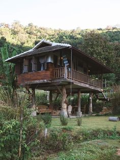 a wooden house sitting on top of a lush green hillside