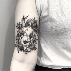 a woman's arm with a skull and flowers tattoo on the left upper arm