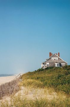 a house sitting on top of a sandy beach next to the ocean