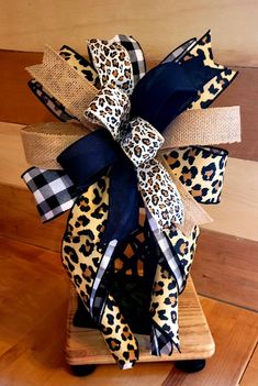 the cheetah leopard print bow is attached to a wooden stand with black ribbon