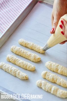 someone is making bread sticks on a baking sheet and using a knife to cut them