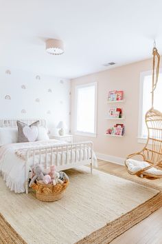 a white bed sitting in a bedroom next to a chair and rug on top of a hard wood floor