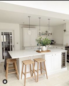 a kitchen with two stools in front of an island and white cabinets on the wall