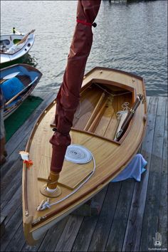 a wooden boat sitting on top of a pier next to the water with other boats in the background