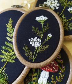 three embroidered hoop frames sitting on top of each other with flowers and plants in them