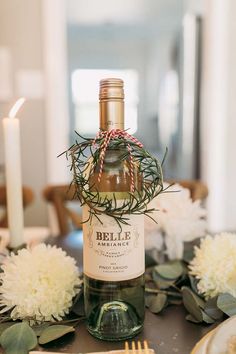 a bottle of wine sitting on top of a table next to some flowers and candles