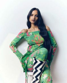 a woman with long black hair wearing a green dress