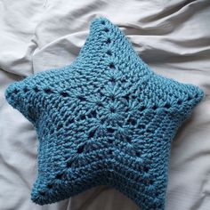 a blue crocheted star pillow laying on top of a bed