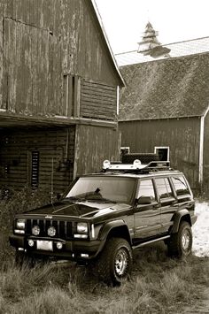 a jeep parked in front of a barn with a radio on top of it's roof