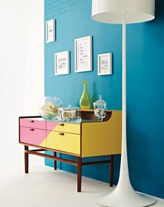 a room with blue walls, yellow and pink furniture and pictures on the wall above it