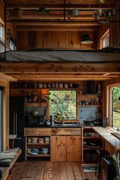 the interior of a tiny cabin with wood flooring and wooden walls, along with an open kitchen area