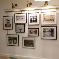 a bunch of pictures hanging on the wall in a room with lights and artwork above them