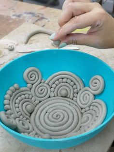 a person is making an art project out of clay in a blue bowl on a table