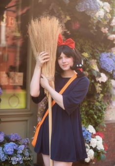 a woman holding a broom in front of flowers