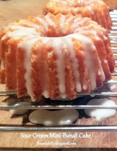 two bundt cakes sitting on top of a cooling rack next to each other with icing