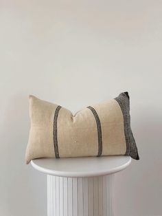 a black and white striped pillow sitting on top of a white table next to a wall