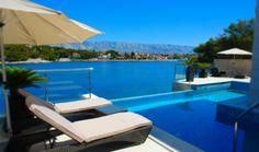 an empty swimming pool with lounge chairs and umbrellas next to it, overlooking the water