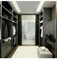 a large walk in closet with lots of clothes on the shelves and an open bathtub