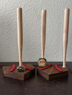 three wooden baseball bats are on display in front of a white wall, with red ribbons around them