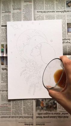 a person holding a glass in front of a paper with a drawing on the side