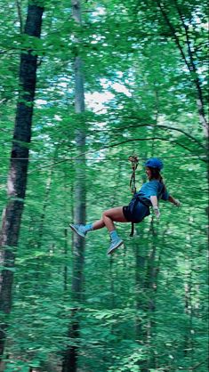 a woman is zipping through the trees on a zip line in the woods,