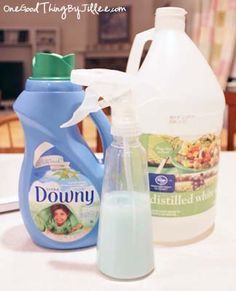 two bottles of downy liquid and a bottle of dishwasher detergent on a table