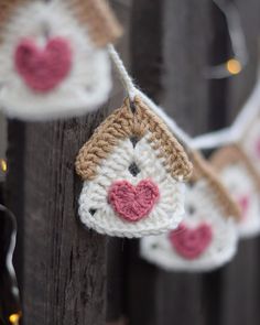 crocheted ornaments hanging from a wooden fence with string lights in the shape of hearts