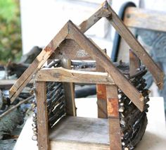 a wooden house made out of chains and nails on top of a white tablecloth