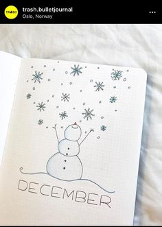 an open notebook with a drawing of a snowman and the words december on it