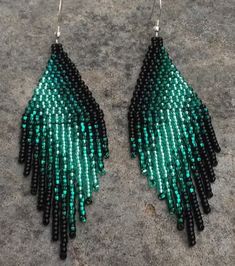 green and black beaded earrings on concrete