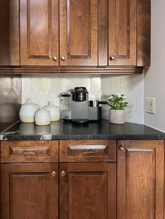 a kitchen with wooden cabinets and black counter tops, including an automatic coffee maker on the center island