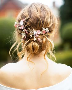 a woman with blonde hair and flowers in her hair is wearing a white dress, looking off to the side