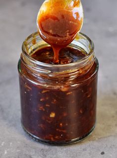 a spoon full of sauce on top of a jar