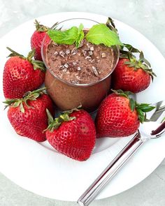 a white plate topped with chocolate pudding and strawberries