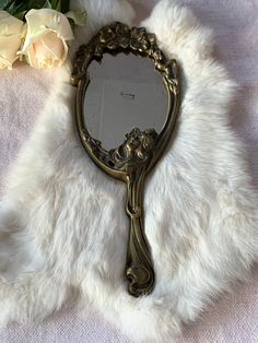 a mirror sitting on top of a white fur covered table next to a flower vase