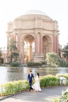 a bride and groom holding hands in front of a pond at the palace of fine arts