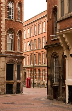 an old brick building with two red telephone booths in the middle of it's courtyard