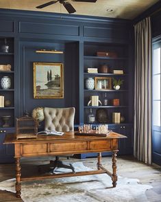 a room with blue walls and shelves filled with books, furniture, and pictures on the wall