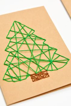 a christmas tree made out of string on top of a piece of brown paper next to a pair of scissors