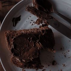 a piece of chocolate cake on a plate with a knife and fork next to it