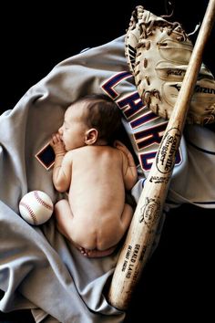 a baby laying on top of a blanket next to a baseball bat