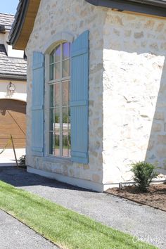 a stone house with blue shutters on the front door and windows in the side