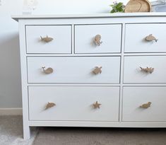 a white dresser with many drawers and knobs