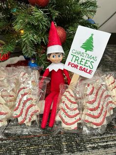 an elf holding a sign next to some cookies