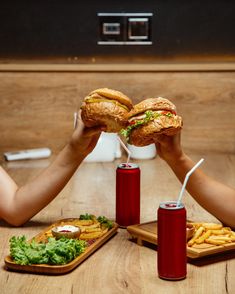 two people holding sandwiches and french fries in front of them