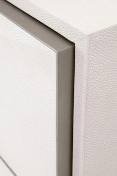 a close up view of the corner of a white cabinet with silver trim on it