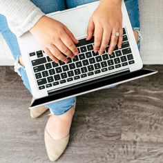 a person sitting on a couch using a laptop computer with their hands resting on the keyboard