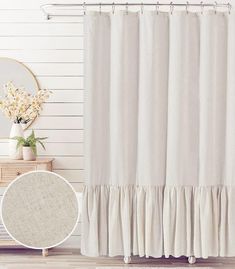 a white shower curtain with ruffles on it next to a mirror and table