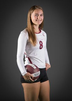 a female football player is posing for a photo in her uniform and holding a ball